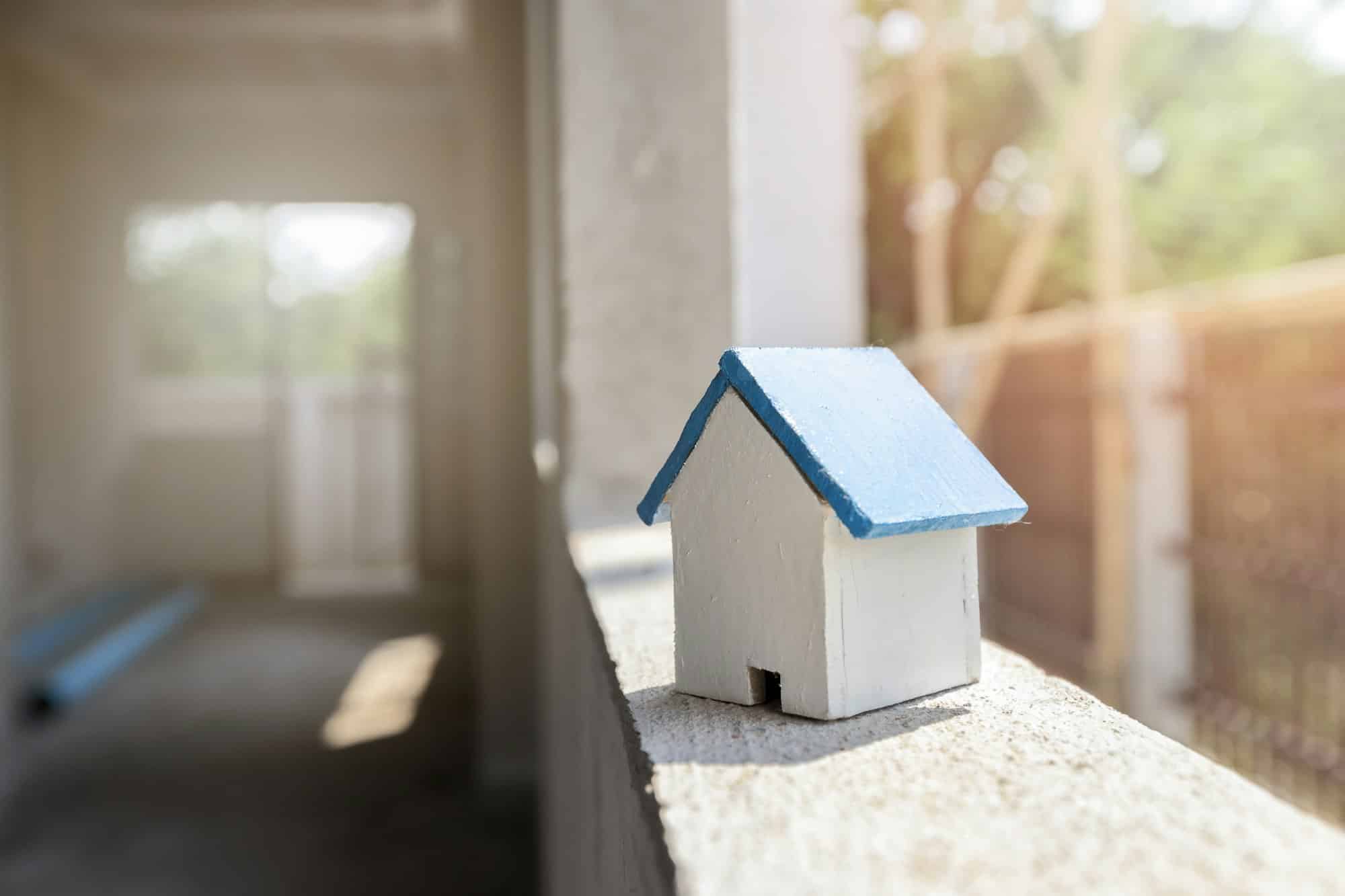 House model on window frame in housing construction site. Architectural concept.