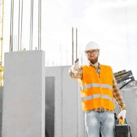 Happy male builder stretching hand for handshake on the background of a concrete wall in the house